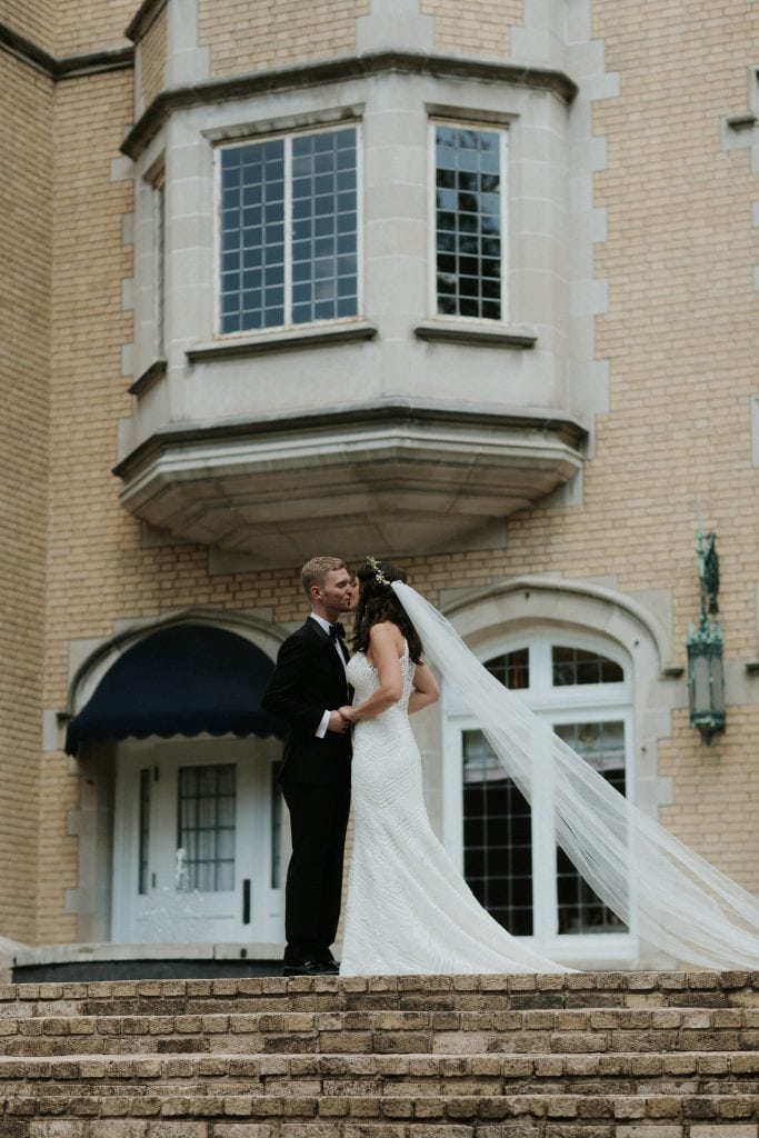 bride and groom standing in front of a mansion