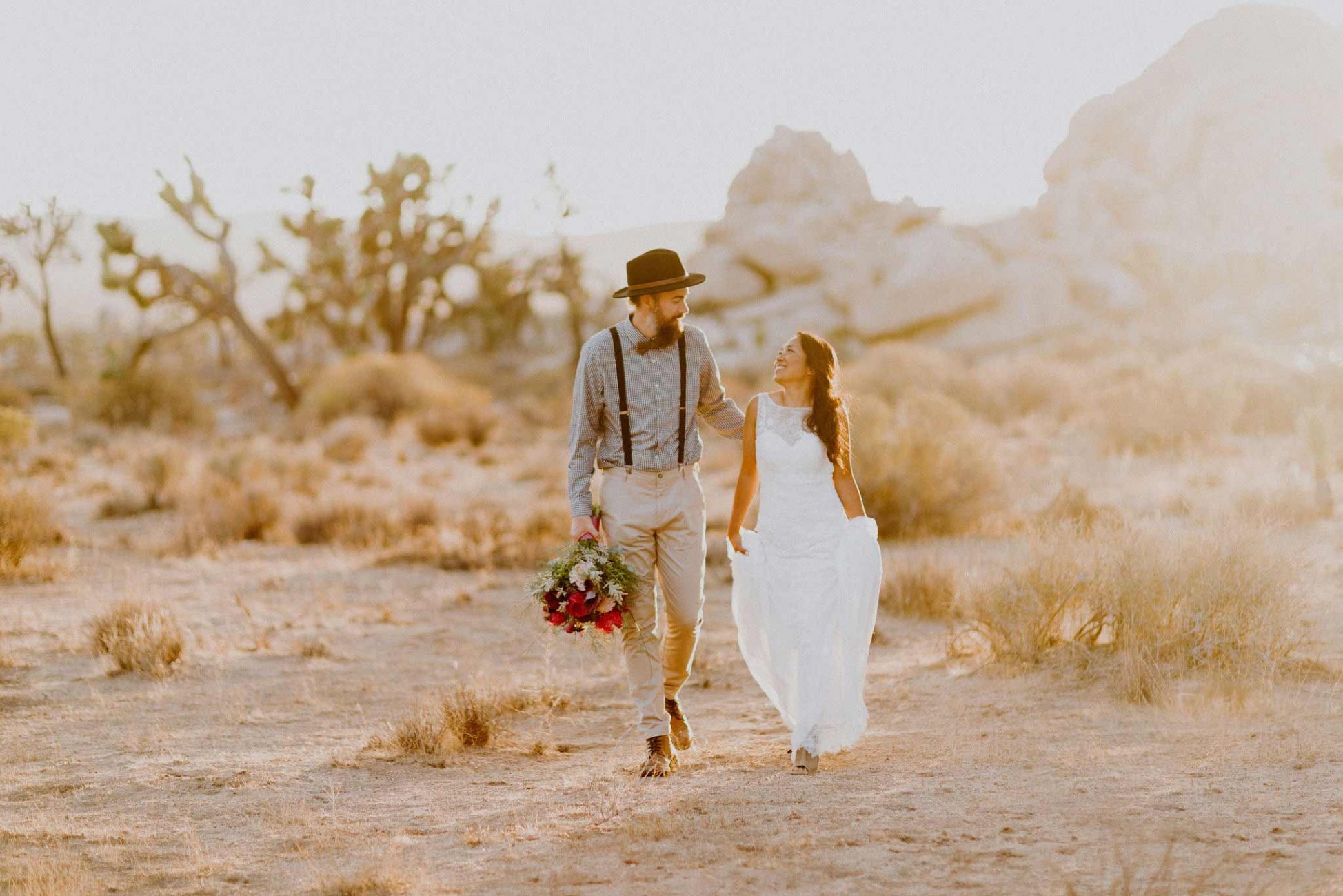 A bride and groom walking in joshua tree national park